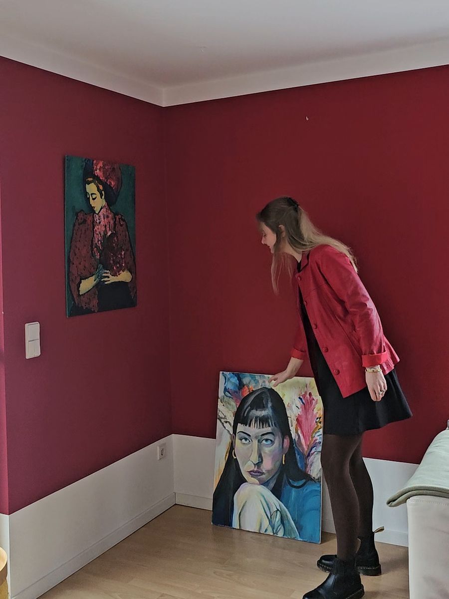 Lena Rothe in ihrem Raum vor zwei eigenen Gemälden